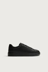Zapatilla de estilo urbano monocolor negro, con cordones al tono, puntera redondeada y suela con volumen.
