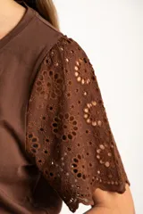 Remera de algodón peinado color negro, con mangas cortas de broderie con diseño calado y terminación festoneada. Presenta un corte oversize y cuello redondo.