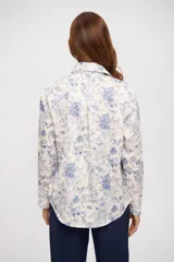 Camisa de manga larga color crema con estampado floral en tonos azules, cuello camisero y escote en V profundo.