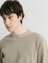 Sweater de punto con textura en color verde oscuro, de cuello redondo y manga larga.