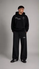 Pantalón de jogging negro de corte holgado, con cintura elástica ajustable mediante cordones y estampado pequeño en la pierna izquierda.