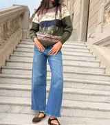 Sweater de tejido de punto artesanal en color verde oliva, con diseño de guardas geométricas y motivos botánicos bordados en tonos blanco, azul y rojo. Presenta cuello redondo, mangas largas y terminaciones en tejido acanalado.