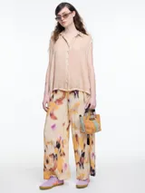 Camisa sin mangas color beige claro con efecto teñido en frío y aspecto gastado. Presenta cuello clásico, cartera oculta y ruedo irregular, más largo en los laterales.