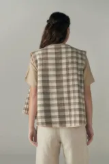 Chaleco color beige con textura tipo espiga, corte holgado y solapa cruzada.