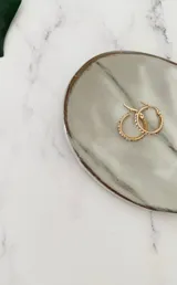 Aros de acero quirúrgico dorado en forma de argolla con incrustaciones de strass en el frente.