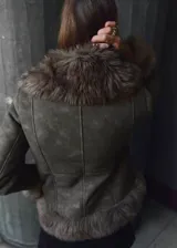 Chaqueta efecto ante color gris oscuro con detalles de pelo sintético en el cuello, solapas, puños y dobladillo. Diseño entallado de manga larga con cierre frontal de ganchos ocultos.