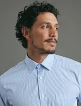 Camisa de vestir de manga larga con diseño de rayas verticales finas en color celeste y blanco. Presenta cuello clásico, cierre frontal con botones y un bolsillo en el pecho.