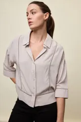 Camisa de calce relajado color celeste, con mangas 3/4, cuello clásico y cierre frontal con botones. Presenta detalles calados en el frente y en las mangas que aportan un acabado delicado al diseño.