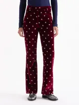 Pantalón de terciopelo color bordó con estampado floral en blanco y verde. Diseño de corte recto, con cierre frontal, gancho y botón interno. Incluye bolsillos delanteros horizontales, bolsillos ojal en la espalda y presillas en la cintura para cinturón.