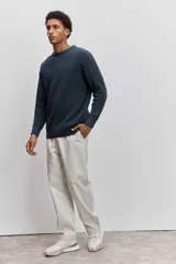 Sweater de tejido de punto acanalado en color marrón, con cuello redondo y ajuste holgado. Presenta un pequeño bordado distintivo en el pecho.