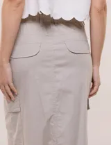 Falda midi estilo cargo de gabardina de algodón color beige, de silueta recta y tiro alto con pretina posterior elastizada. Cuenta con bolsillos funcionales diagonales, laterales tipo cargo con solapa y traseros con tapa, además de tajo frontal inferior.