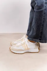 Zapatillas deportivas color blanco con detalles en beige y suela marrón.