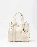Cartera mediana color crudo de simil cuero, con doble asa de mano, correa ajustable y desmontable, bolsillo frontal con botón a presión, detalles de herrajes plateados y dije colgante en forma de corazón. Cuenta con el logotipo de la marca grabado en la parte frontal.
