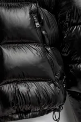 Campera puffer negra con capucha, cierre frontal con cremallera, bolsillos laterales con cremallera y puños elásticos.