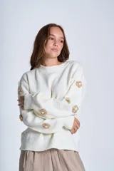 Sweater color crema de hilado frizado con cuello redondo y apliques de flores color beige en las mangas.