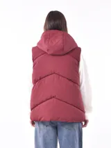 Chaleco acolchado negro con capucha y cierre frontal de cremallera y broches.