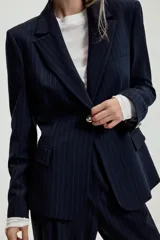 Blazer entallado de color azul marino con estampado de rayas diplomáticas, cuello con solapa, hombreras, manga larga y cierre frontal con un botón. Cuenta con bolsillos delanteros con solapa.