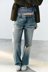 Jeans de tiro bajo y corte recto, color celeste con efecto lavado. Presenta diseño de doble tiro con detalle de short superpuesto con roturas, además de roturas adicionales en las perneras. Cuenta con cinco bolsillos, trabillas para cinturón y cierre frontal con cremallera y botón metálico.