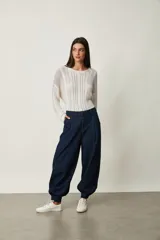 Pantalón tipo jean azul oscuro, de corte slouchy con pinzas en la cintura, bolsillos laterales y puños fruncidos con elástico en los tobillos.