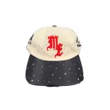 Gorro con visera de color beige y visera negra, con bordado frontal en relieve rojo y detalles de strass distribuidos por toda la prenda.