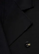 Abrigo largo de diseño oversize con doble botonadura, cuello con solapas de muesca y hombros caídos. Cuenta con dos bolsillos laterales y abertura posterior en el bajo.