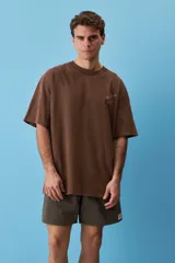 Remera marrón oversize de manga corta, con cuello redondo y pequeño estampado gráfico en el pecho.