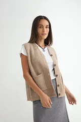 Chaleco de tejido de punto en color beige, con escote en V, cierre frontal con botones oscuros y dos bolsillos delanteros aplicados.
