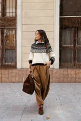 Sweater de lana con diseño de jacquard en la parte superior, cuello redondo, mangas largas y puños acanalados. Presenta un corte holgado con tajos laterales y un diseño ligeramente más corto en la parte delantera.