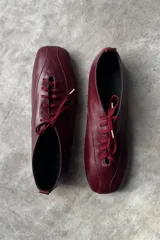 Zapato tipo flat de cuero amarillo con cordones frontales y punta cuadrada.