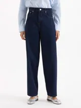 Pantalón de jean azul oscuro de tiro alto y silueta slouchy, con costuras a la vista y cierre frontal con botón metálico.