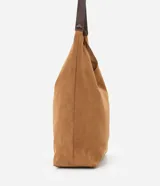 Cartera tipo hobo de gran tamaño confeccionada en material sintético efecto gamuza color tostado. Presenta una estructura flexible, asa única en tono contrastante y cierre mediante botón a presión.