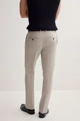 Pantalón de vestir color beige, corte slim fit, con pliegues, bolsillos laterales y traseros ribeteados con botón.