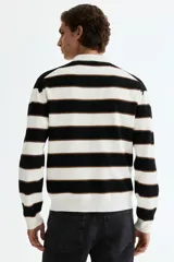Sweater de punto suave con diseño a rayas horizontales en blanco, negro y marrón, cuello polo con abertura en V y manga larga con puños acanalados.