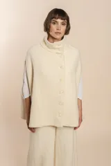 Capa color beige con textura de espiga, cuello alto con botones y aberturas laterales para los brazos. Confeccionada en lana fina sin teñir.