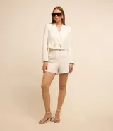 Bermuda de sastrería color blanco, confeccionada en crepé, con trabillas en la cintura, cierre delantero y bolsillos simulados.