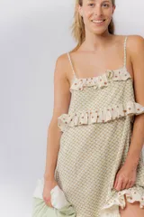 Camisón corto de algodón estampado en color crema con diseño de pequeños rombos verdes. Presenta tirantes finos, escote recto y volados en el pecho y el ruedo, con un estampado de lunares marrones sobre fondo crema.
