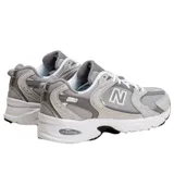 Championes New Balance 530 de estilo retro, color gris con detalles en blanco y negro, confeccionados con malla transpirable y superposiciones de material sintético. Cuenta con tecnología ABZORB en la entresuela para mayor amortiguación y suela de goma.