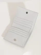 Billetera pequeña de cuero vacuno graneado con estampado de piel de serpiente en tonos grises. Tiene cierre con broche imán, divisiones internas para tarjetas y forrería de tejido jacquard. Presenta matelasseado y aplique Lipstick característico de la marca.