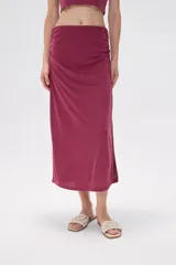 Falda midi de corte tubo confeccionada en modal, con detalle de frunces laterales que aportan movimiento y ajuste al cuerpo.