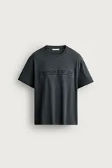 Camiseta relaxed fit de manga corta y cuello redondo, color gris oscuro, con estampado en relieve tono sobre tono con la palabra 'MODULE' en el frente.