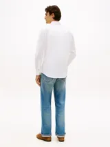 Camisa de twill blanca de manga larga, con cuello flexible, cierre frontal de botones y detalles distintivos de la marca Tommy Hilfiger.