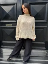 Sweater color crema con cuello alto y diseño de trenzas.
