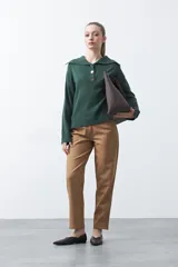 Sweater de tejido de punto color azul marino, con cuello polo amplio y cierre frontal con tres botones metálicos. Presenta mangas largas levemente acampanadas y un diseño de silueta relajada con aberturas laterales en el ruedo.