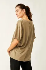 Remera de tela liviana con caída fluida, de calce oversize, con escote redondo, mangas cortas con puño enrollado, hombros caídos y ruedo curvo.