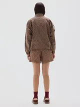 Campera de estilo deportivo con cierre frontal, confeccionada en denim con estampado de rombos en tonos marrones y paneles en color crudo. Presenta cuello alto, puños y cintura elásticos, y detalle de etiqueta con logo en el pecho.