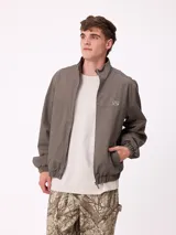 Campera Rusty de corte clásico, color negro, con cierre frontal completo, cuello alto y puños elásticos. Presenta un diseño minimalista con el logo de la marca bordado en el pecho.