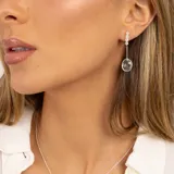 Aros colgantes de plata 925 con tres pequeñas piedras de la luna y una piedra de topacio azul ovalada.