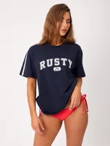 Remera Rusty azul marino de corte holgado, con cuello redondo, mangas cortas con franja blanca lateral y estampado tipográfico frontal de la marca.