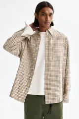 Camisa de sarga de algodón con estampado a cuadros en tonos beige y marrón, cuello americano, cierre frontal de botones, un bolsillo de parche en el pecho y mangas largas.