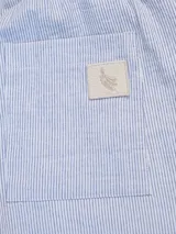 Pantalón celeste a rayas verticales blancas, de corte recto, con cintura elástica y cordón ajustable.